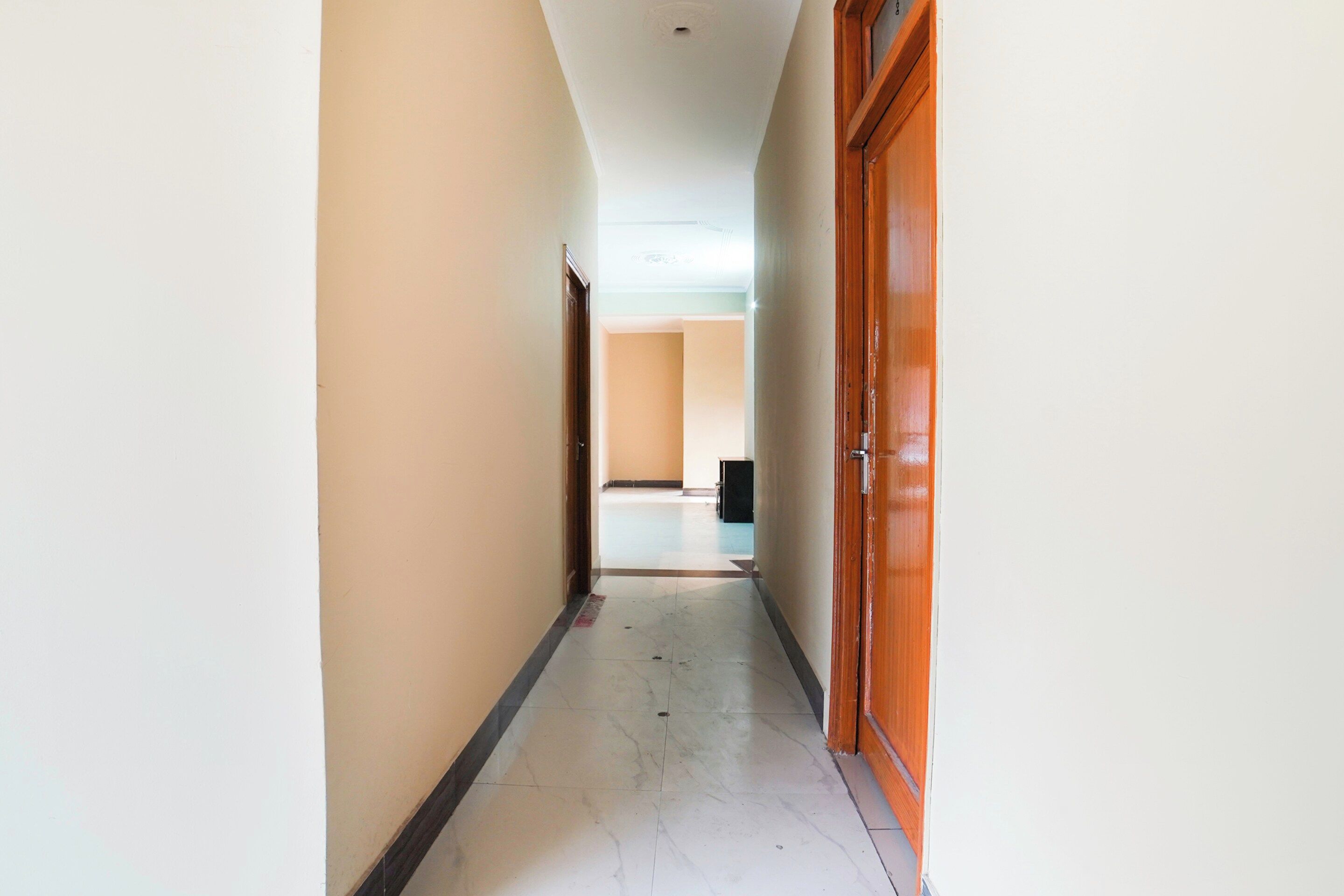 Un pasillo con una puerta de madera a la derecha y una pared blanca a la izquierda.
