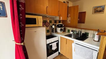 Una cucina compatta con forno a microonde, fornello, lavandino e un piccolo frigorifero.