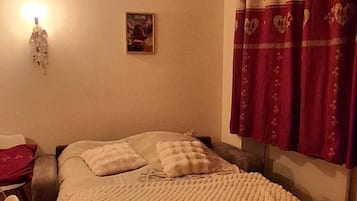 Una camera da letto con un letto, una sedia, una lampada a muro e una tenda.