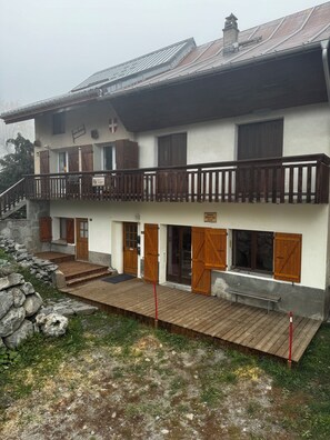Een gebouw met twee verdiepingen, een balkon, houten deuren en een stenen muur.