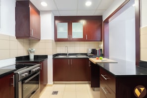 Una cocina con gabinetes de madera, estufa de acero inoxidable, microondas y un lavabo.