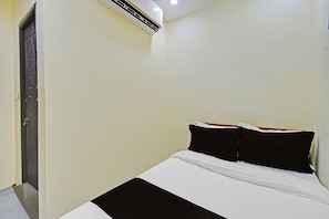 A room with a bed, a door, and an air conditioning unit.