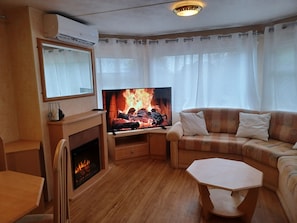 A living room with a fireplace, a television, a sofa, and a coffee table. - New Listing (Peyrilhac)