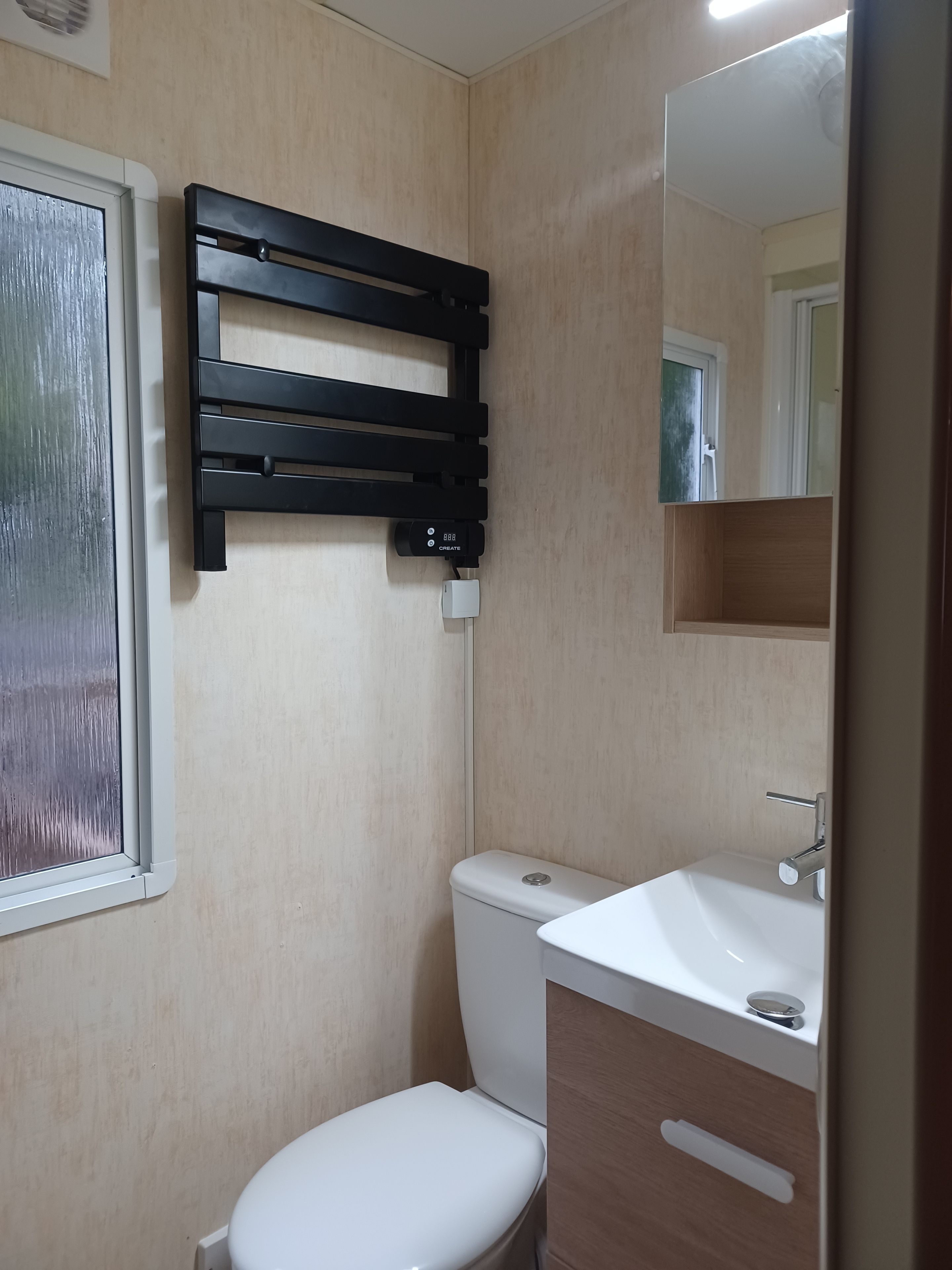 A bathroom with a toilet, a sink, a mirror, and a towel rack.
