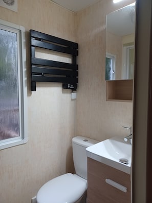 A bathroom with a toilet, a sink, a mirror, and a towel rack. - New Listing (Peyrilhac)