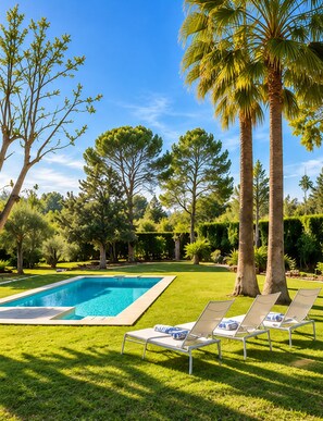 Ein Schwimmbecken mit Liegestühlen und Palmen in einem angelegten Garten.