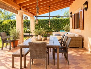 Eine Terrassengaststätte mit einem Holztisch, Stühlen, einer Couch und einer Uhr an der Wand.