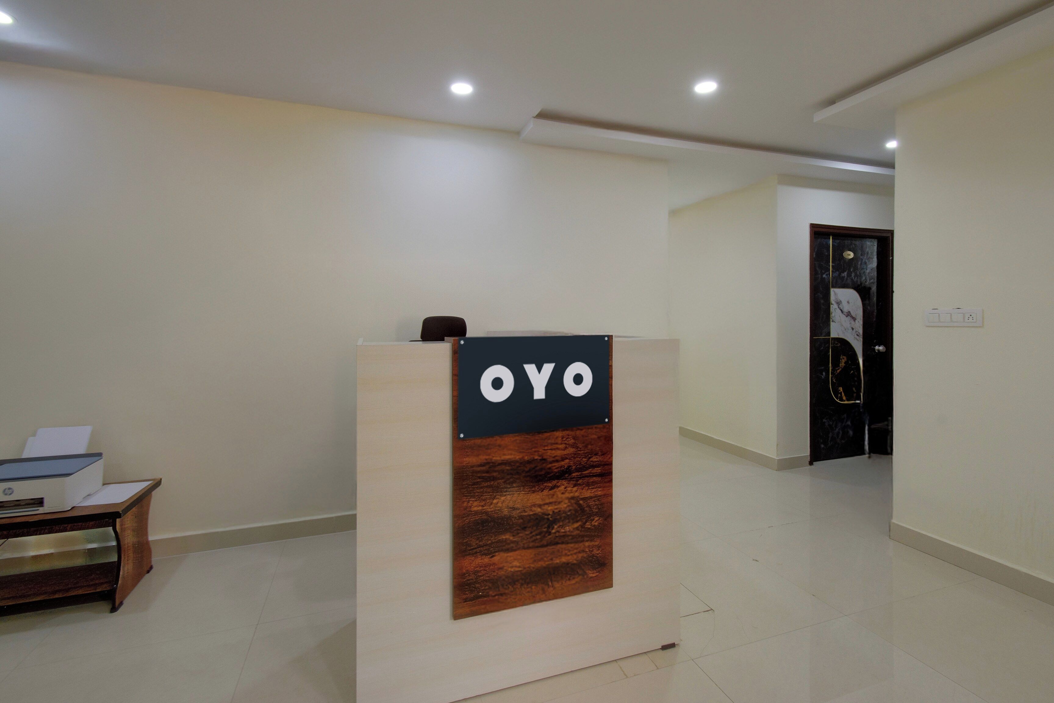 A reception desk with a sign that reads 'OYO' in a modern hotel lobby with a clean, minimalist design.