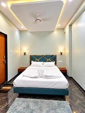A hotel room with a bed, nightstands, a ceiling light, and a door. - SRG Hotel and Restruant (Borgaon)