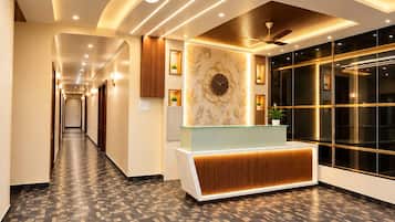A hotel lobby with a reception desk, a patterned floor, and a ceiling with recessed lighting.