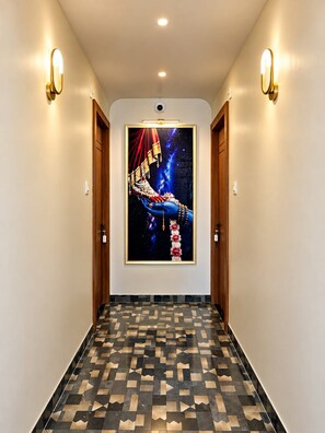 Un couloir doté d’un revêtement de sol à motifs, d’œuvres d’art encadrées accrochées au mur et d’un éclairage fixé au mur.