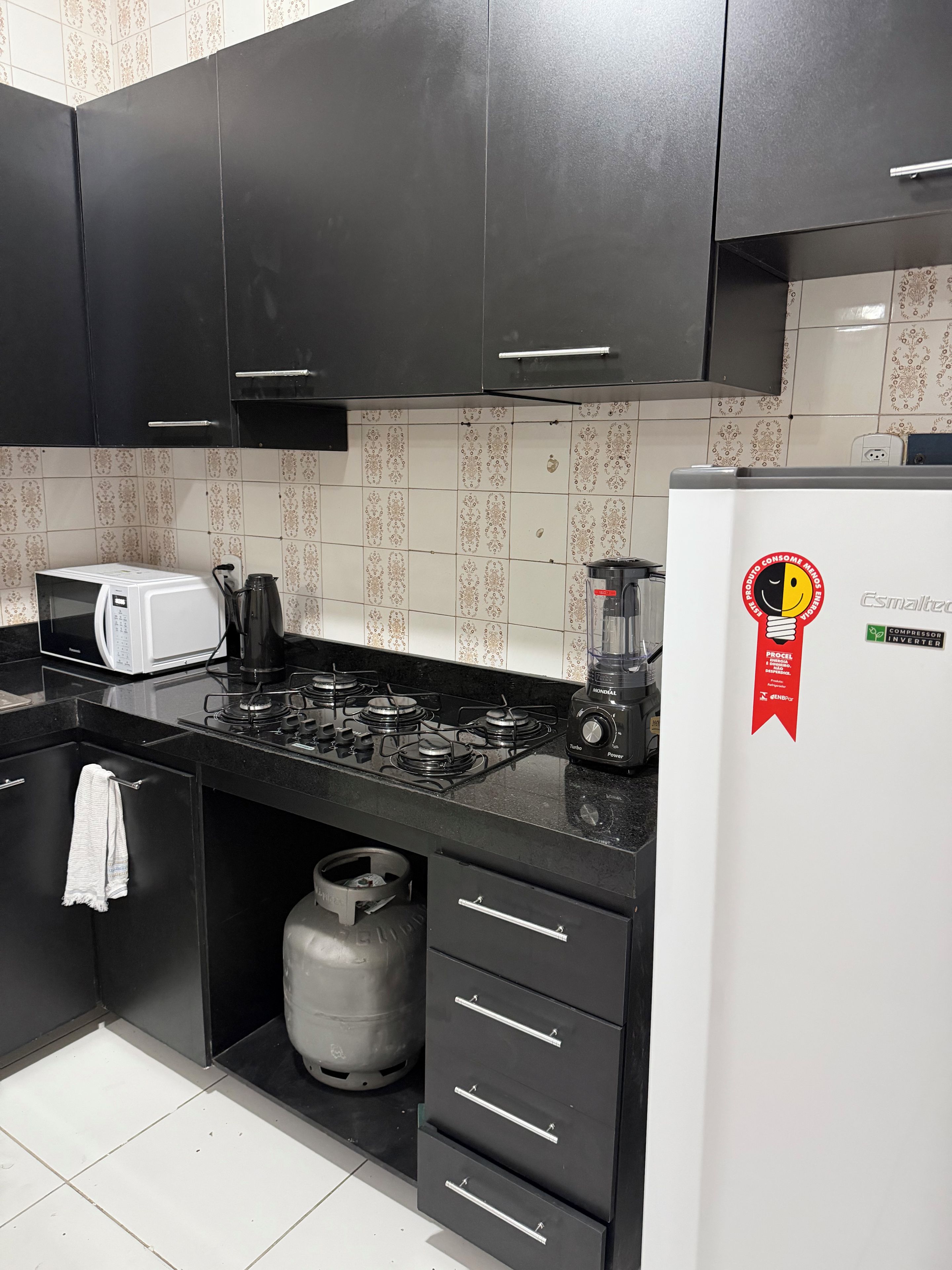 Una cucina moderna con mobili neri, un frigorifero bianco, un fornello a gas e una macchina da caffè.