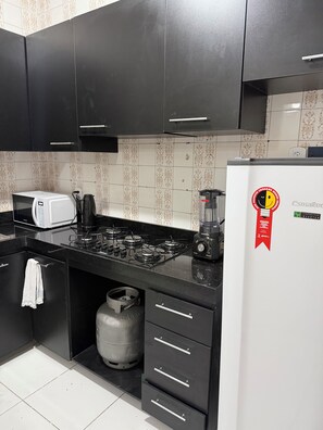 Una cucina moderna con mobili neri, un frigorifero bianco, un fornello a gas e una macchina da caffè.