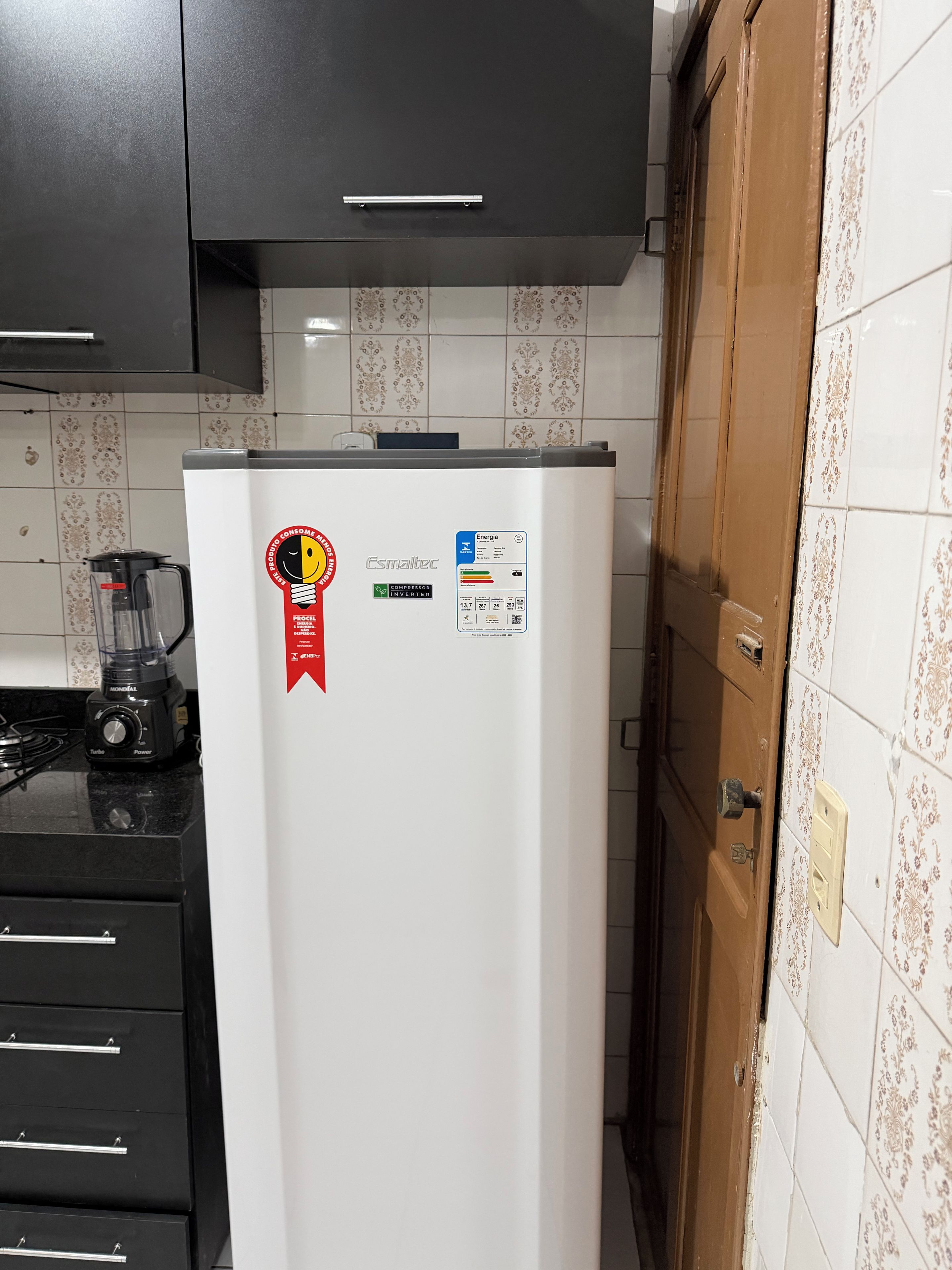 Una cucina con un frigorifero bianco, una stufa nera e una porta in legno.