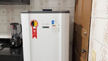 Una cucina con un frigorifero bianco, una stufa nera e una porta in legno.