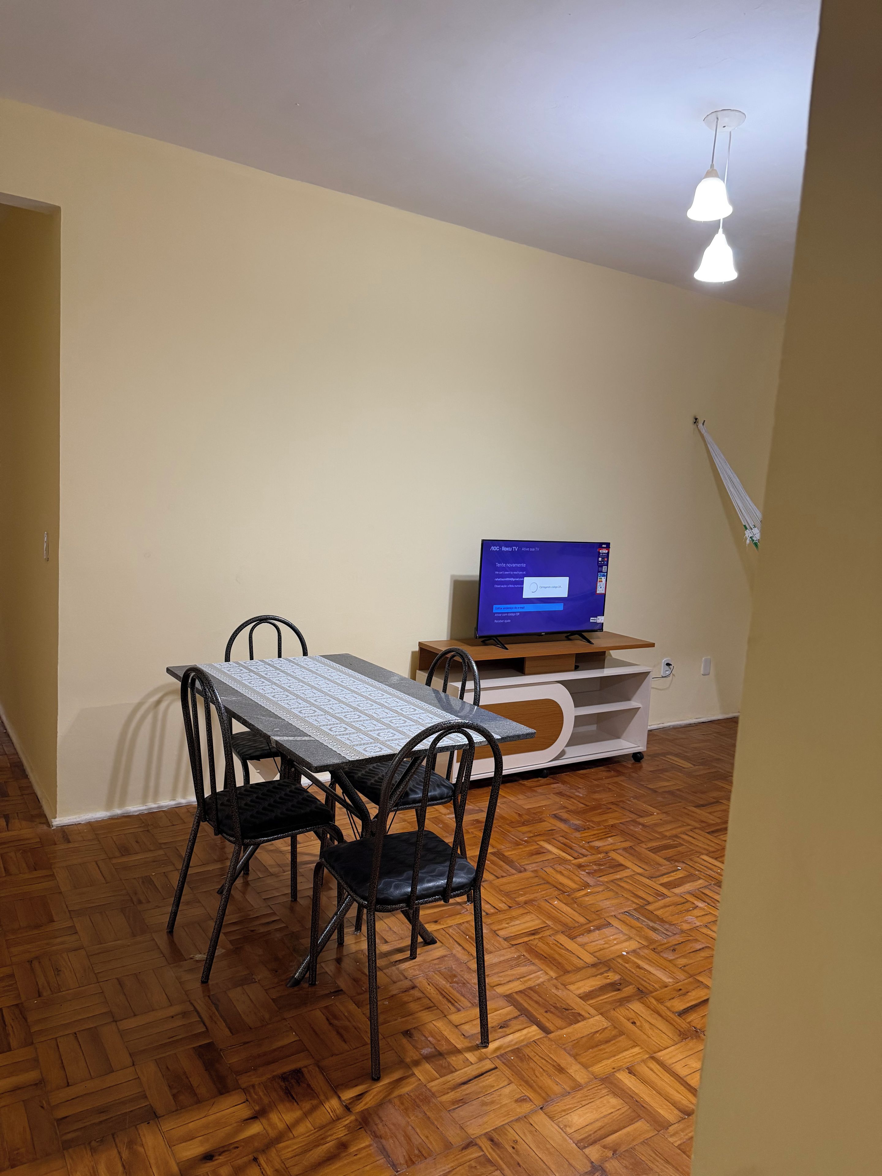 Un'area pranzo con tavolo e sedie, una televisione su un mobile e una luce a soffitto.
