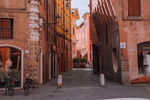 Una calle estrecha con edificios históricos, una bicicleta y pequeños pilares.