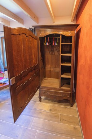 Un armari de fusta amb porta de mirall, barra penjant i estant.
