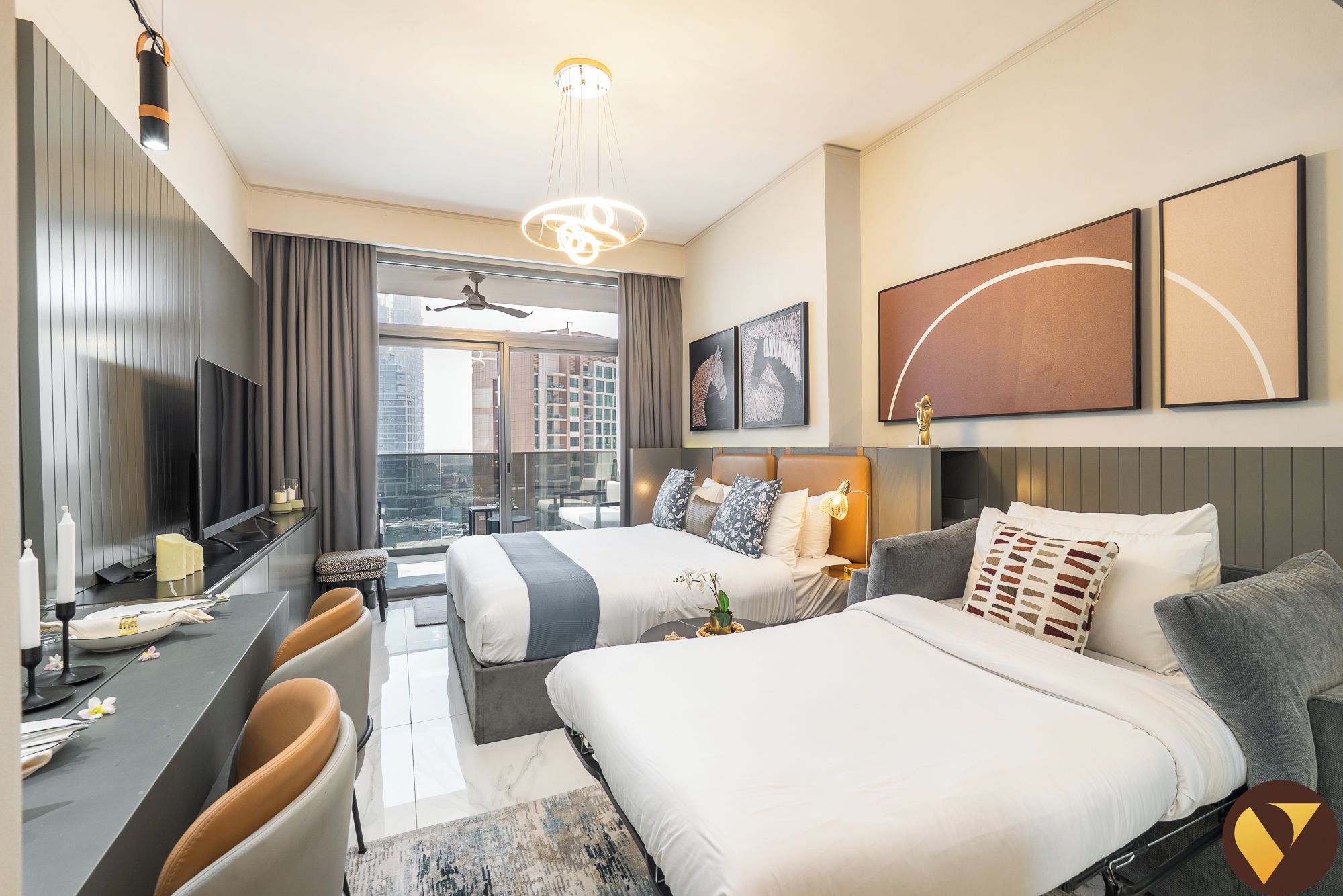 Une chambre d’hôtel moderne avec deux lits, un bureau avec des chaises, une grande fenêtre donnant sur la ville et des œuvres d’art accrochées aux murs.