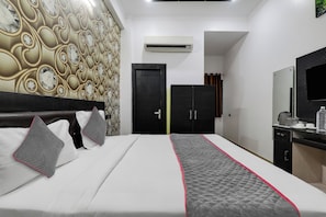Een hotelkamer met een bed, een kledingkast, een spiegel en een airconditioner.
