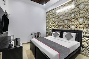 Een hotelkamer met een bed, een bureau, een stoel en een wand met een decoratief patroon.