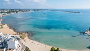 Eine Vogelperspektive einer Küstenlandschaft mit Strand, klarem blauen Wasser und Gebäuden entlang des Ufers.