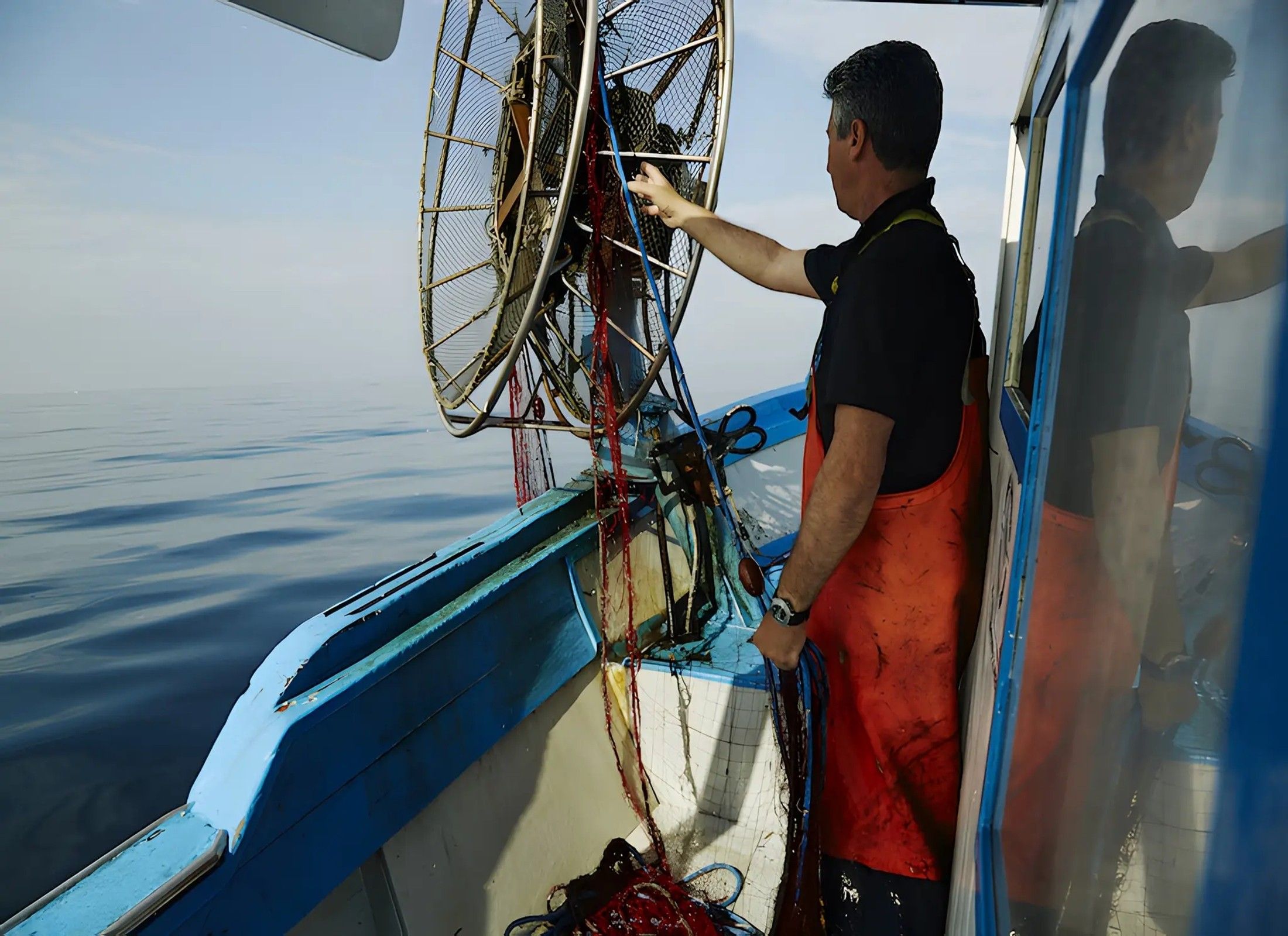 Eine Person auf einem Boot, das ein großes Fischernetz bedient.