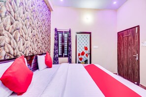 Una camera d'albergo con un letto grande, un pannello decorativo, una porta con motivo floreale e un armadio.