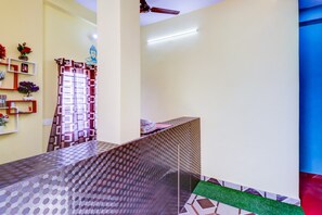 Una stanza con pavimento decorato, una reception e una mensola a parete con oggetti ornamentali.