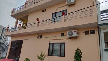 A multi-story building with balconies, air conditioning units, and a red scooter parked in front.