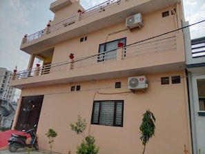 A multi-story building with balconies, air conditioning units, and a red scooter parked in front. - Hotel O By OYO R K Residency SGPGI (Lucknow)
