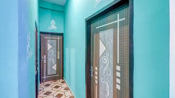 A hallway with teal walls, patterned floor tiles, and doors with decorative designs.