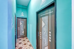 A hallway with teal walls, patterned floor tiles, and doors with decorative designs. - Hotel O By OYO R K Residency SGPGI (Lucknow)