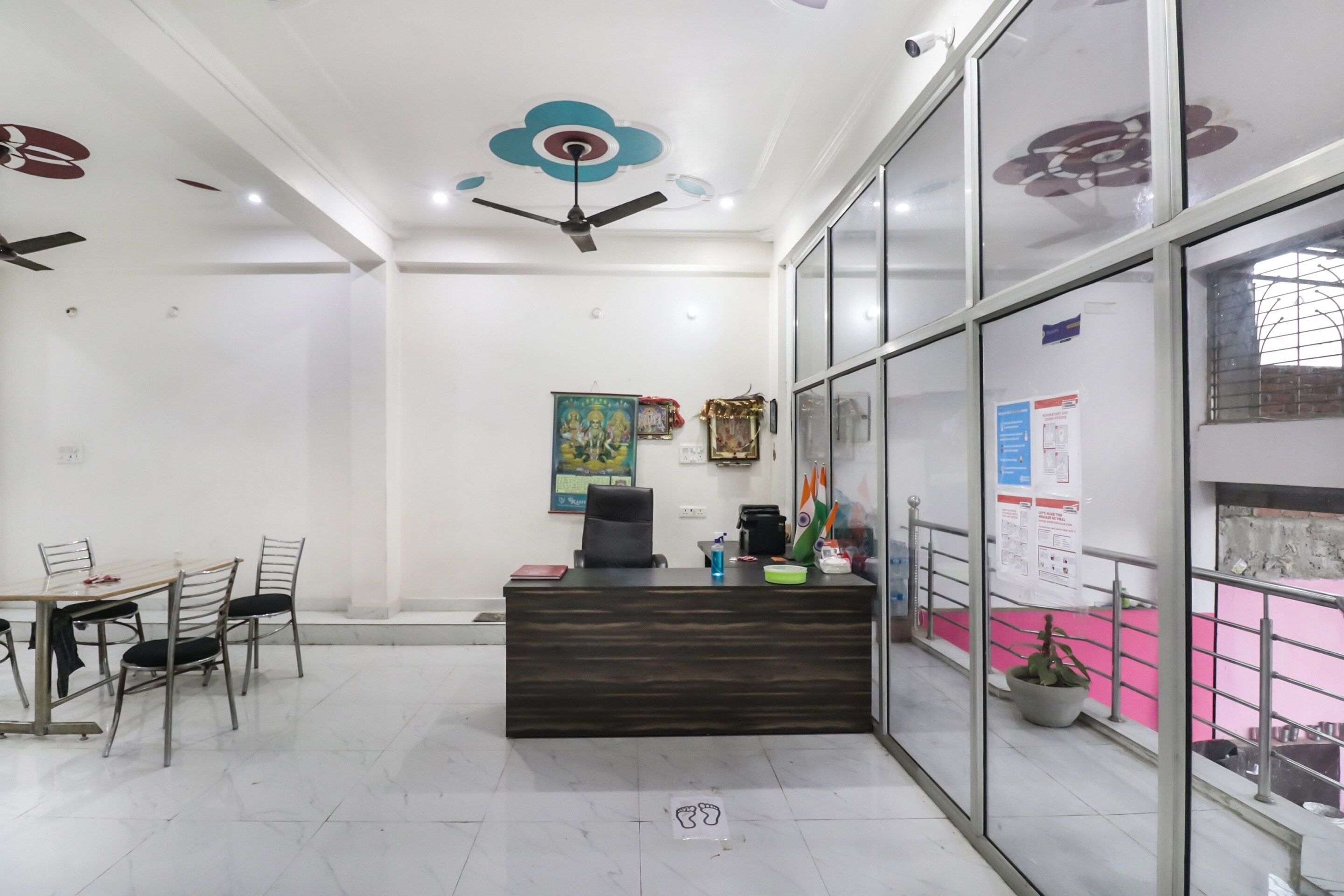Un'area reception con scrivania, sedie, una ventola a soffitto e una parete con manifesti informativi.