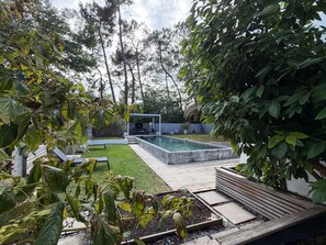 Un espace piscine extérieur moderne, doté d’une terrasse en bois, de chaises longues et d’une pergola.