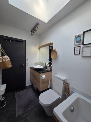 Un baño moderno con tragaluz, inodoro, lavamanos y bañera.