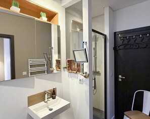 Casa de banho moderna com lavatório branco, espelho e zona de duche.