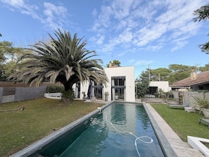 A modern house with a swimming pool, a palm tree, and a well-maintained lawn. - Guest Room 'Maison Océâme - Chambre 1' with Shared Pool, Wi-Fi and Air Conditioning (Capbreton)