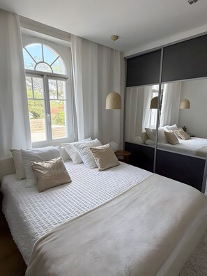 Quarto com cama grande, guarda-roupa e janela com cortinas.