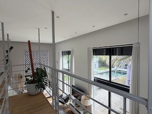 Un interior moderno con una escalera, un ventanal con vistas a una piscina y una planta en maceta.