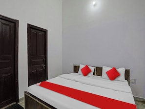 Una habitación con una cama, dos puertas y un aplique en el techo.