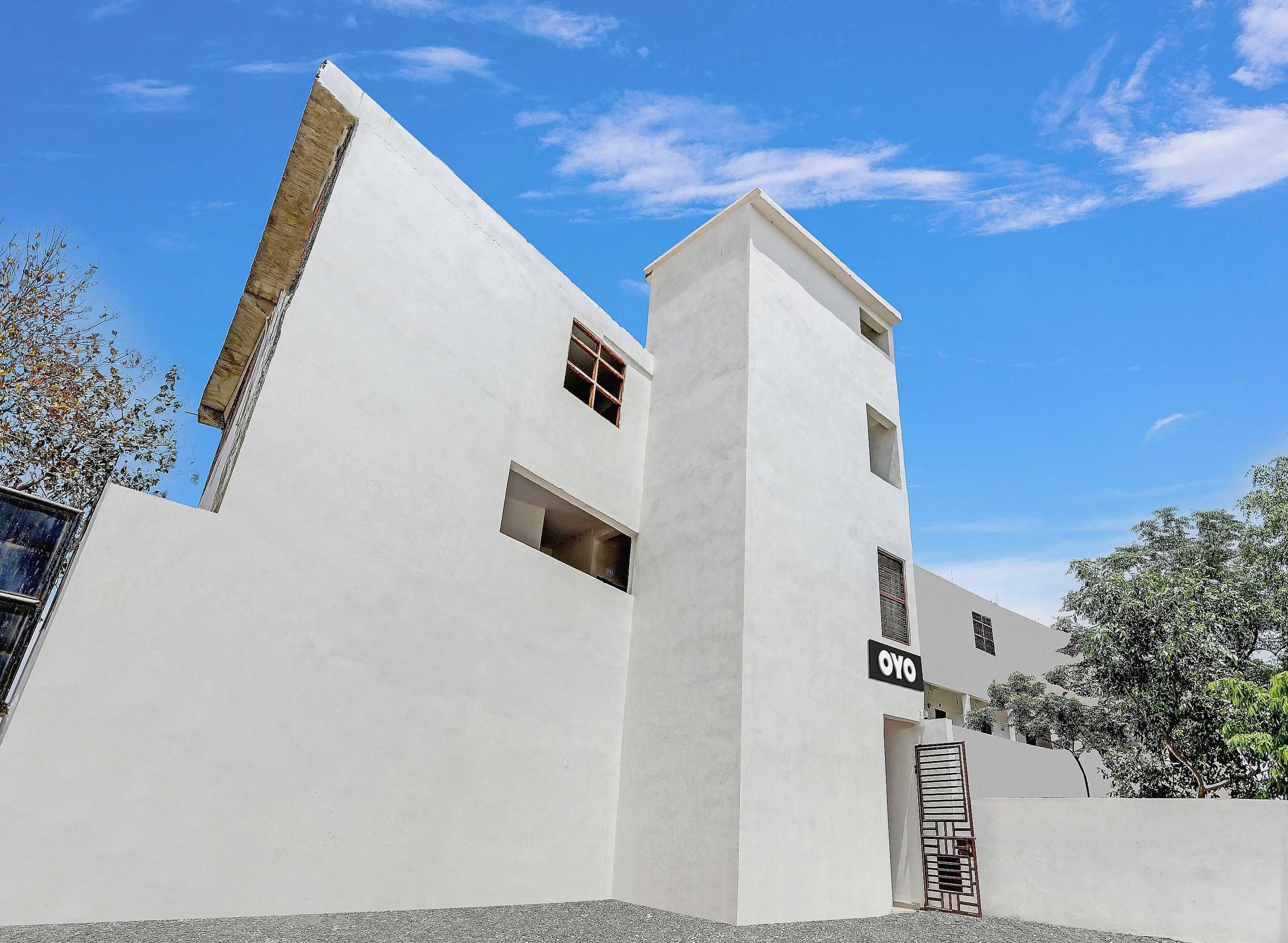 Un edificio moderno con fachada blanca, un cartel que dice 'OYO' y una entrada con portón.