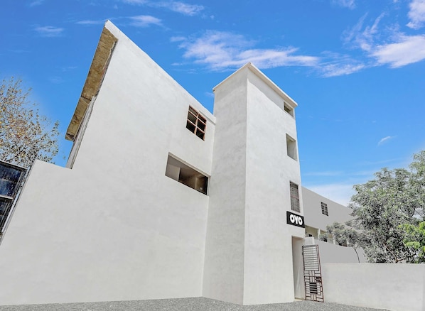 Un edificio moderno con fachada blanca, un cartel que dice 'OYO' y una entrada con portón.