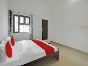 Un dormitorio con cama, ventana con cortinas, una puerta y un interruptor de luz en la pared.