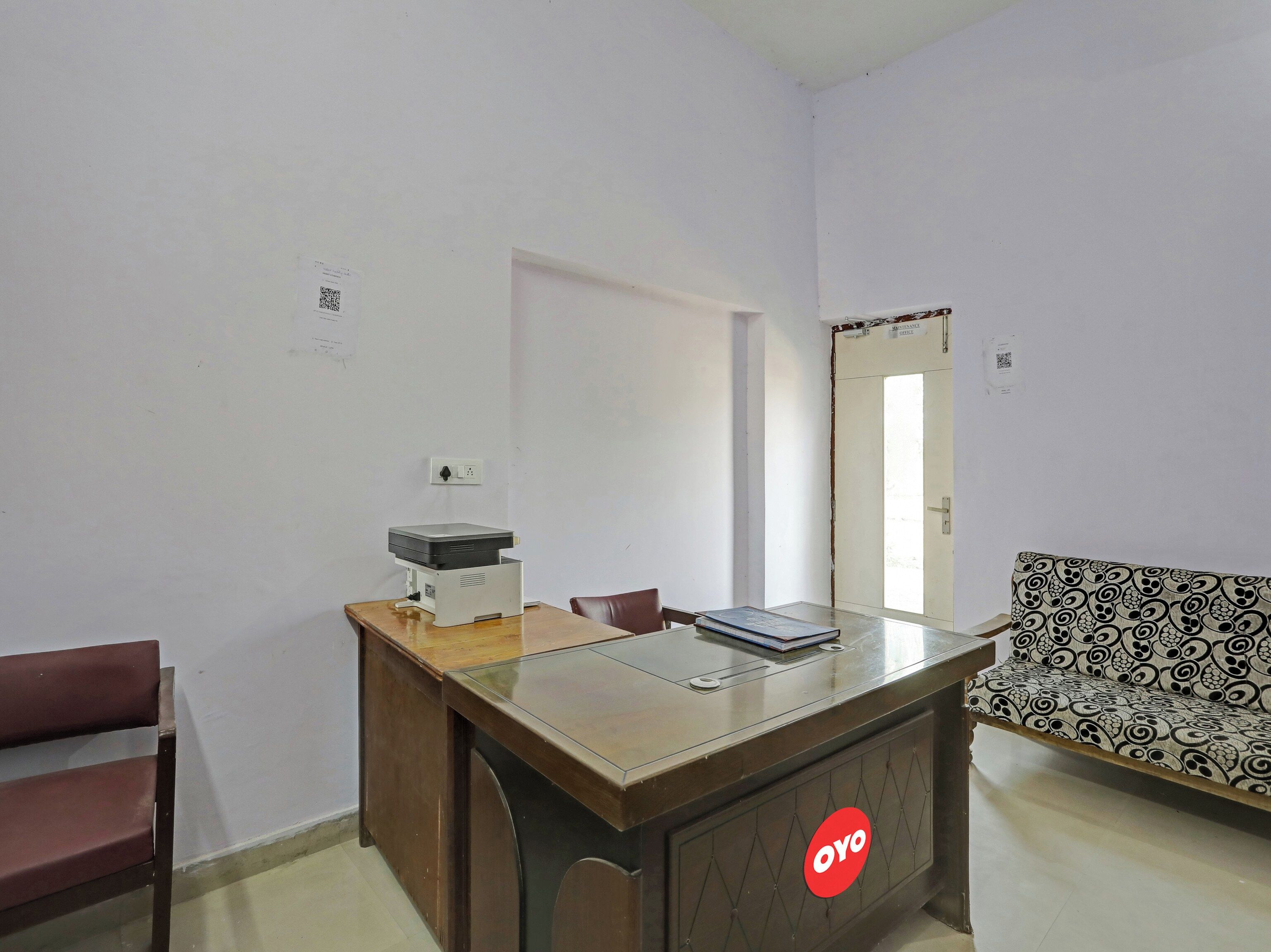 Una habitación con un escritorio de madera, una silla, un sofá y una puerta.