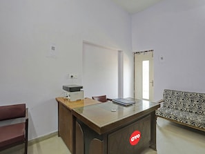 Una habitación con un escritorio de madera, una silla, un sofá y una puerta.