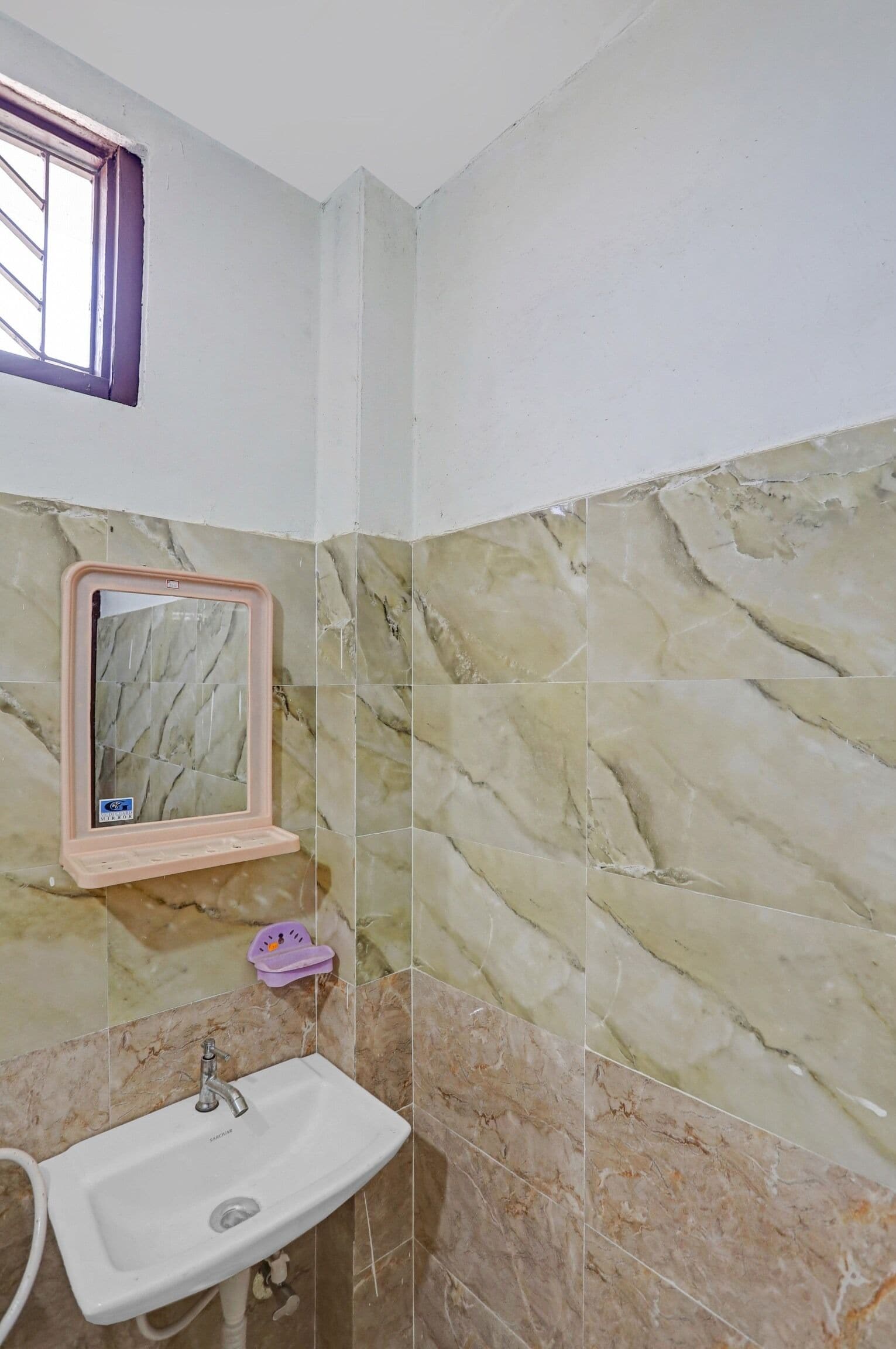 Une salle de bain avec un lavabo, un miroir et des murs décorés d’un motif imitant le marbre.