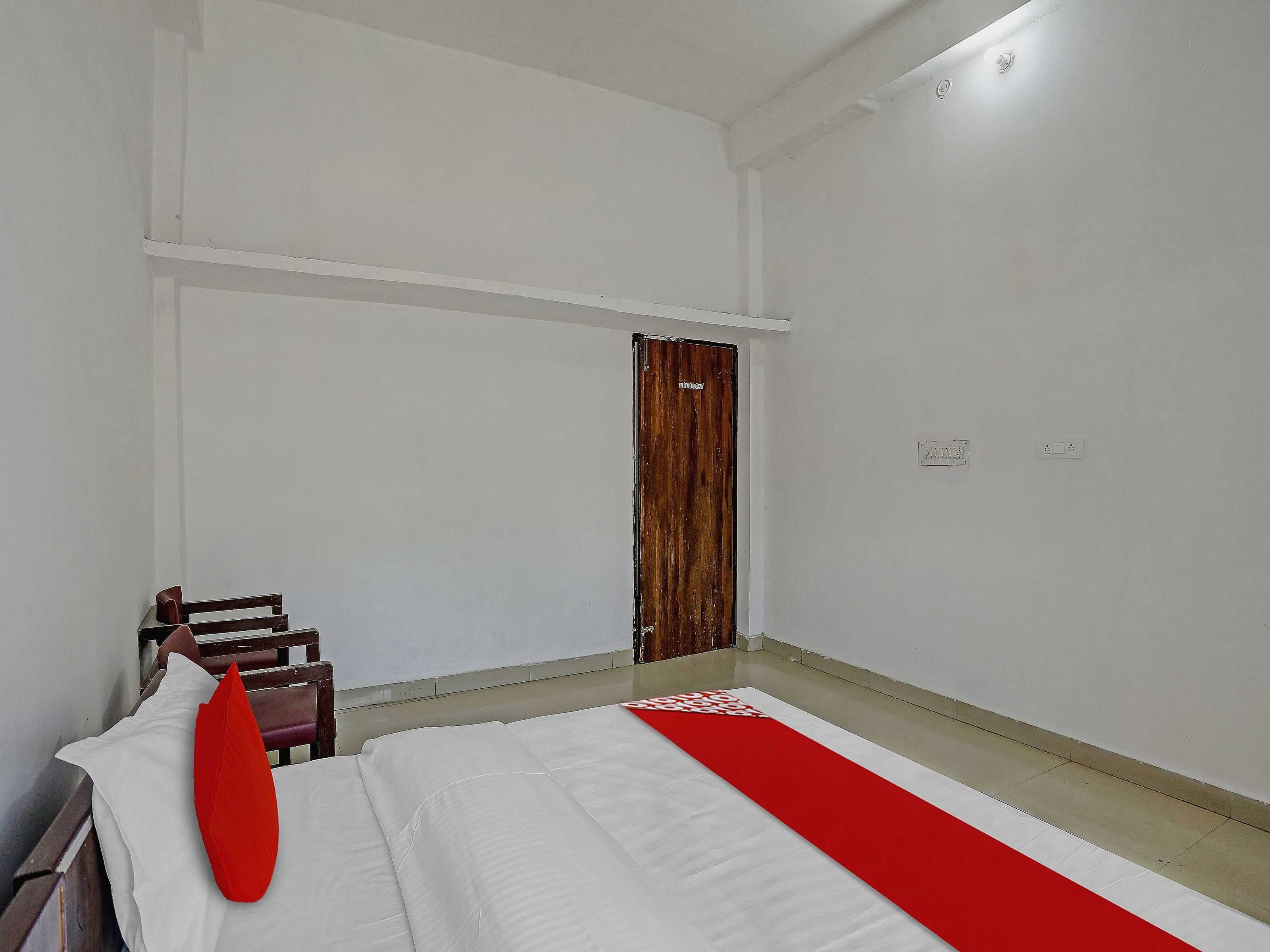 Une chambre d’hôtel avec un lit, une porte en bois et un tapis rouge.