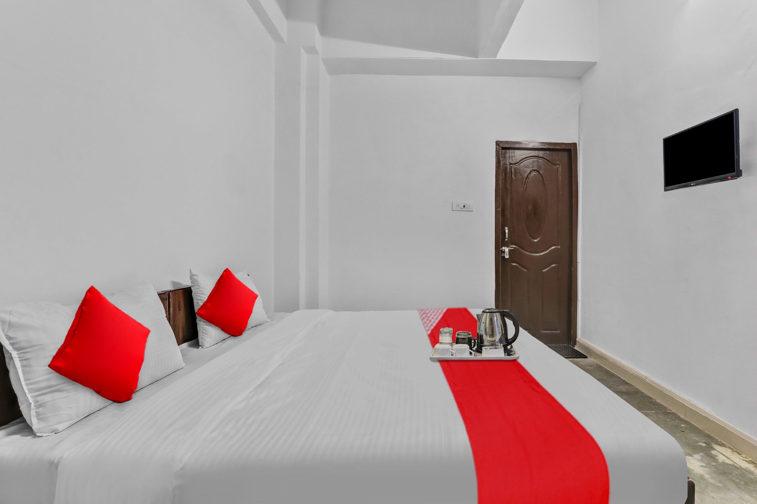 A hotel room with a bed, a coffee maker, and a TV on the wall.