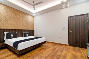 Un dormitorio con cama, cabecera de madera, ventilador de techo y una puerta.